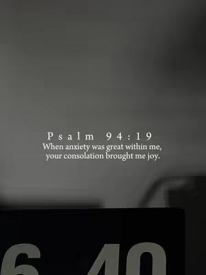 A grayscale image featuring text in the center, overlaid against a blurred background that appears to be an indoor setting. The text is a quote from Psalm 94:19. At the bottom, a blurred digital clock is visible.