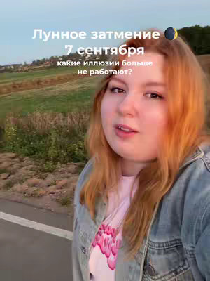 A woman with red hair stands in front of a field and road, with text overlaid on the photo about a lunar eclipse.