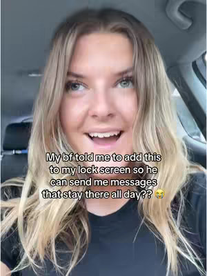 A selfie-style video cover image shows a woman in a car, smiling at the camera. Her blonde hair is parted on the side, framing her face. She is wearing a black shirt. The text overlay reads: 'My bf told me to add this to my lock screen so he can send me messages that stay there all day??'