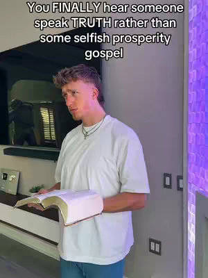 A man in a white t-shirt stands indoors holding an open book. Text overlay is visible at the top.