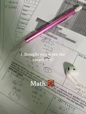 The image captures a top-down view of a math problem sheet scattered with notes, calculations, and circled answers, highlighted by a bright pink mechanical pencil lying across it. In the foreground sits a white AirPod, adding a modern touch to the scene. The background is filled with other sheets of paper that are blurred, creating depth; text overlays include the phrase 'I thought you were the smart one?' set above the word 'Math'.