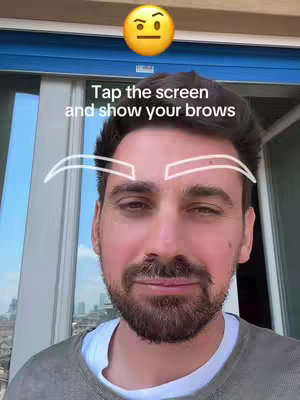 A man is centered, looking at the camera with a semi-serious facial expression. Above his head is a yellow emoji with a questioning face. The text overlay says 'Tap the screen and show your brows'.