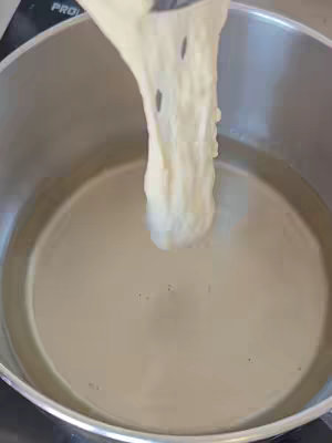 The cover image shows a close-up of a metal pot filled with oil. A piece of dough is being held above the oil, appearing to be in the process of frying. The dough is light in color, and the oil appears to be hot.