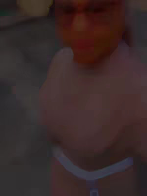 The cover image is a close-up shot of a person wearing sunglasses. The image is slightly blurred and has a warm, reddish tint. The person's face is partially visible, and they appear to be wearing a white top or garment. The background is dark and indistinct.