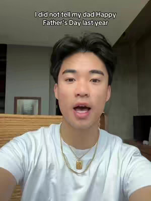 A young man with dark hair and fair skin is centered in the frame, speaking with an open mouth. He's wearing a white t-shirt and a gold necklace. Text overlays the top of the frame.