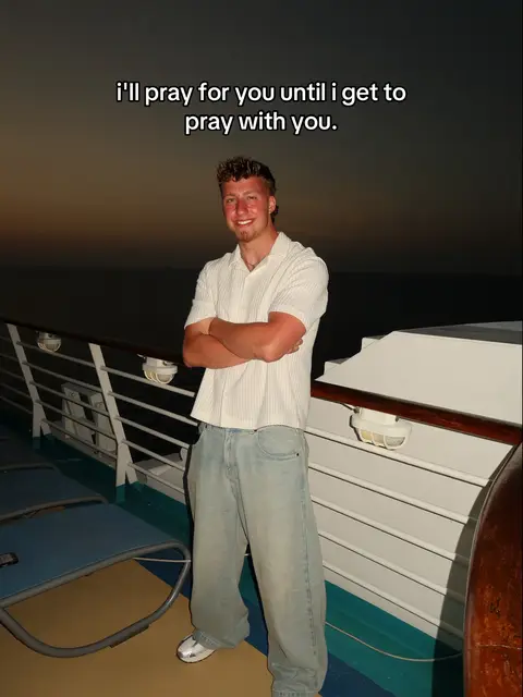 Image shows a young man standing on a cruise ship deck, a sunset in the backdrop. He has short brown hair, wearing a white shirt and light-wash jeans, with arms crossed. Text overlay saying, "i'll pray for you until i get to pray with you."