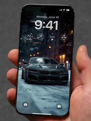 A hand holding a smartphone displaying a live wallpaper. The wallpaper shows a black car driving on a road with snowy conditions, and buildings and street lights in the background. The time, date, and other phone details are displayed at the top of the screen.