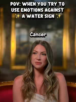 A selfie-style shot features a woman in a seated position with a soft background. The main subject is a fair-skinned woman with long, wavy blonde hair. She is wearing a light-colored top and has a neutral expression. The background is somewhat blurred and appears to be a room with golden tones, possibly a wall with artwork or decorative elements. Overlay text in bold font is placed at the top, and a text box with the word 'Cancer' is at the middle.