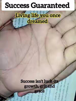 The cover image features a close-up of an open palm with additional text overlays. The hand is well-lit, and the image is slightly blurry, focusing the viewer's attention on palm lines. The overall composition is designed to highlight the palmistry theme. At the top, we have the title 'Success Guaranteed', and a secondary hook text along the top of the palm, 'Living life you once dreamed'. At the bottom of the palm, we can see text 'Success isn't luck-its growth, grit and grace.'
