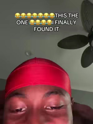 A selfie-style video cover image shows a person wearing a red durag, from the shoulders up. The person's eyes are visible, and they are framed at a slightly upward angle with text overlaid at the top. A ceiling fan partially visible in the background.