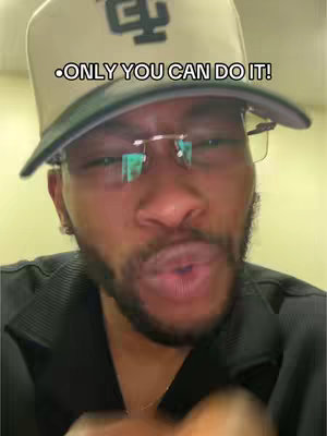 Image features a close-up of a Black man wearing a beige baseball cap and glasses, with visible text overlay. The man is looking towards the viewer and appears to be talking.
