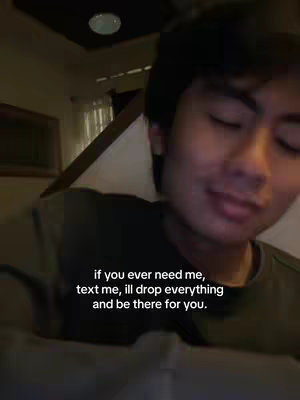 A young man with dark hair is shown in a dimly lit interior setting. The man is positioned slightly to the right of the frame, with most of his face visible and eyes partially closed. Text is overlaid on top, providing a caring message.