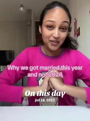 A woman in a pink top is seated in front of a white surface. Text overlays read \"Why we got married this year and not 2024\" and \"On this day Jul 18, 2023\". The background includes a television and overhead lighting.