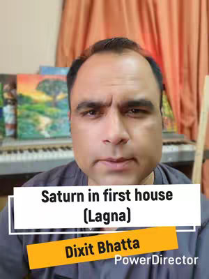 A man with short dark hair looks directly at the camera. A text overlay at the bottom of the frame reads: "Saturn in first house (Lagna)". Below this is a bar with "Dixit Bhatta". The background has a piano, art, and curtains.