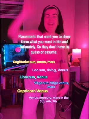 A woman is standing in a room lit by a pink light. The image is filled with text that presents different zodiac placements in a text overlay. The woman is smiling and appears to be mid-dance.