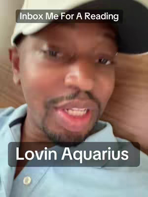 A man in light blue shirt and a baseball cap looks straight at the camera while talking. The background is somewhat out of focus, suggesting a casual setting. Text overlays read 'Inbox Me For A Reading' and 'Lolin Aquarius'.