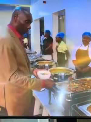 The cover image shows a man in a brown blazer holding a bowl, standing in a brightly lit room near a buffet. Other people, including individuals wearing white aprons, are visible in the background, near food warmers filled with food.