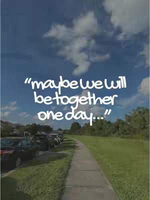 A scenic shot featuring a clear blue sky dotted with puffy white clouds. A paved pathway leads into the distance, flanked by green grass on one side and parked cars on the other. The text overlayed on the image says "maybe we will be together one day..."