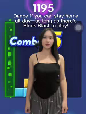 A woman stands centered in front of a mobile block puzzle game background. She wears a black top and gray patterned pants. Text overlays the top reads 'Dance if you can stay home all day—as long as there's Block Blast to play!'