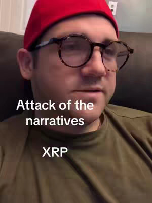 A man in a red cap and glasses is the central focus of a selfie-style video cover image. The text overlay reads 'Attack of the narratives'. The man is looking slightly to his left with a neutral expression, set against a softly lit background.
