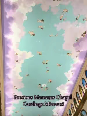 The cover image shows a section of a painted ceiling with a light blue background. Numerous cherubic figures are depicted floating amidst fluffy white clouds. The upper portion of the image showcases a purple border with the start of a decorative wall. Text at the bottom says, "Precious Moments Chapel Carthage Missouri".