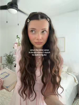 A woman with long, wavy brown hair stands in front of a blurred background including a bed and dresser with a book in her hand. She looks to the side with a slightly surprised expression, wearing a light pink dress and a cross necklace. Text overlayed suggests a story about online dating and biblical references.