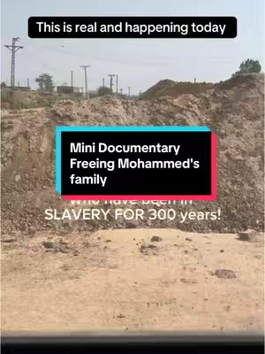 The image shows a mostly barren, light brown landscape with a few scattered plants and small hills in the background. Overlaid on the image are text elements enclosed in rectangles. One rectangle contains the text "This is real and happening today", while another contains the text "Mini Documentary Freeing Mohammed's family". At the bottom of the image, there is text saying "SLAVERY FOR 300 years!". The colors are muted, with dominant earth tones of brown and beige.