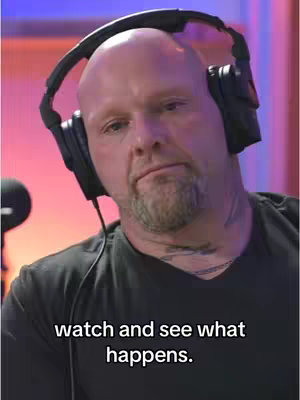 A middle-aged man with a shaved head and a goatee wears a black shirt and headphones. He looks downward with a slightly concerned expression. Text on the bottom says, "watch and see what happens."