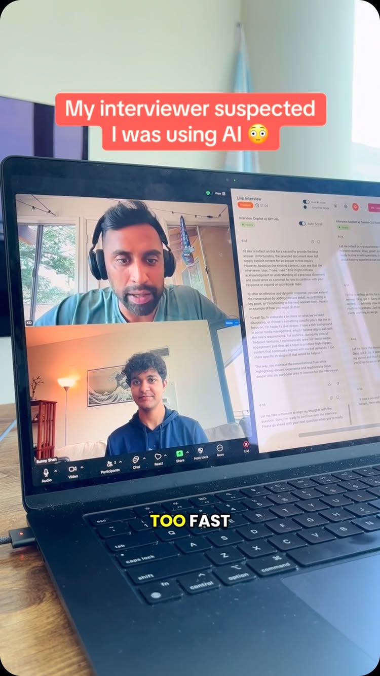A laptop is open, displaying a video call of two men. An overlay at the top reads, "My interviewer suspected I was using AI." Below, text reads "TOO FAST." The scene inside the laptop shows the two men in separate video call frames. The setting is modern, with interior backdrops.