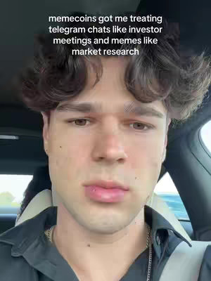 A young man with brown curly hair is shown close-up, inside a car. He is wearing a black shirt and a silver chain, and the background shows a blurry view of outside the car. Text at the top of the image reads: "memecoins got me treating telegram chats like investor meetings and memes like market research."