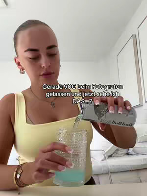 A young woman with her hair pulled back is pictured, pouring a liquid from a Red Bull can shaped container into a glass with a light blue liquid already in it. The woman wears a yellow top and jewelry. Text is overlaid on the image.