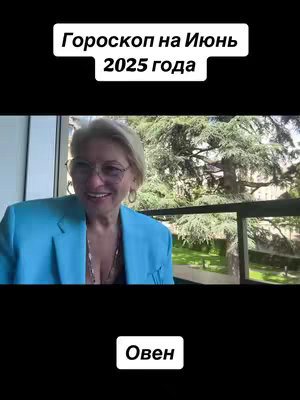 A woman in a blue blazer and glasses smiles at the camera; text overlays appear as headers and footers, indicating an astrological horoscope about Aries for June 2025; behind her is a scenic outdoor view.
