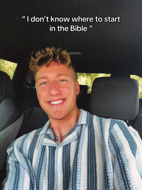 The image shows a young man smiling widely while seated in what appears to be a car. He has short, tousled blonde hair, fair skin, and is wearing a blue and white striped button-down shirt. The background is dark, suggesting a car interior, with a glimpse of green foliage visible through the car window. The text overlay in the image says, “I don't know where to start in the Bible.” This suggests the video may discuss the start of reading the Bible.