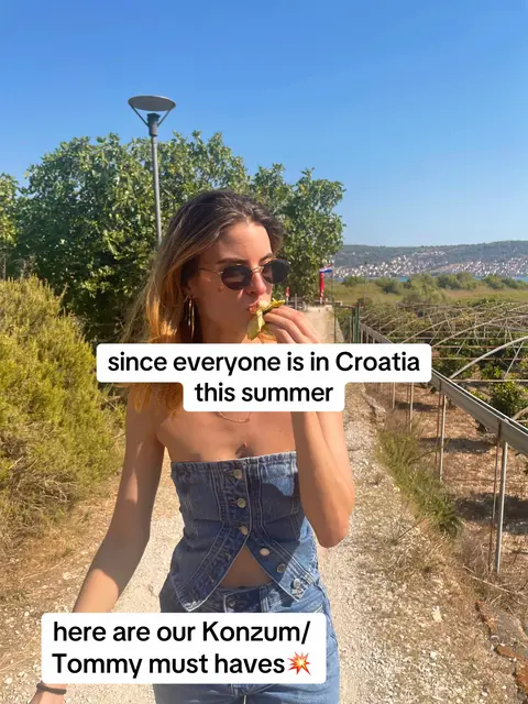 A woman in sunglasses and a denim top is walking on a path with greenery on either side, and a blue sky backdrop. Overlay text states 'since everyone is in Croatia this summer' and then 'here are our Konzum/ Tommy must haves'.