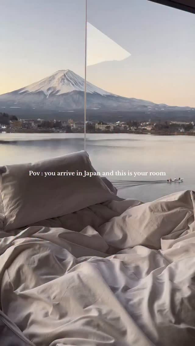 The cover image captures a serene bedroom scene offering a breathtaking view of Mount Fuji. In the foreground, rumpled, light-colored bedding suggests a cozy, inviting atmosphere, with a pillow centrally positioned. Through a large window, the iconic snow-capped Mount Fuji dominates the background skyline, complemented by a tranquil lake and a hint of a small town along its shore. The composition uses natural lighting to enhance the calm, picturesque scene.