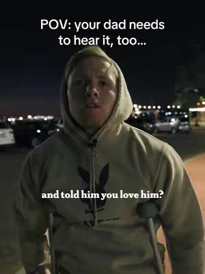 A man wearing a hoodie stands outside at night, facing the camera. Overlaying text indicates this is a POV shot. In the background, there are cars and lights. The man has a crutch under his arm