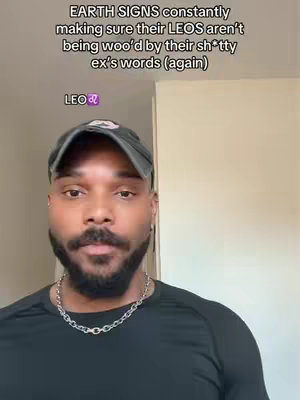 A close-up shot of a man, possibly a creator, facing the camera. He has short hair and a mustache. He's wearing a dark baseball cap and a dark shirt. Text overlays are at the top, with "EARTH SIGNS constantly making sure their LEOS aren't being woo'd by their sh*tty ex's words (again)". Below this text, the word "LEO" is shown, along with the zodiac sign. The background is light.