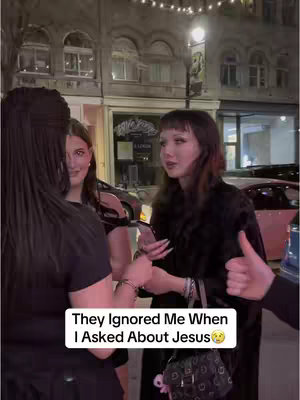 The cover image shows a street scene at night, with three women and an arm giving the thumbs up. The hook text is inside a white box: "They Ignored Me When I Asked About Jesus". The woman on the right is holding a phone and has on a black jacket and holding a black bag. The background is made up of buildings with street lights.