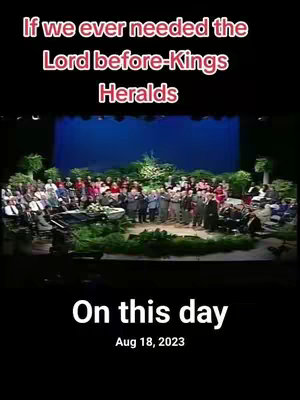 The image shows a stage setting with a group of people. The text overlayed contains the phrase "If we ever needed the Lord before… Kings Heralds." At the bottom, there's text indicating "On this day, Aug 18, 2023". The background seems to be a stage with a blue curtain. All seems to center around a religious gathering.