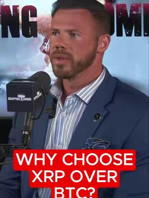 A man in a blue blazer and a patterned shirt is speaking. A microphone is present in the foreground. The background features a blurry backdrop and the video's hook in the bottom.