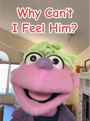 A close-up shot of a puppet with a large pink face, a purple nose, and large black eyes. The puppet has green hair and is wearing a plaid shirt. The caption "Why Can't I Feel Him?" is in red, stylized text above the puppet.