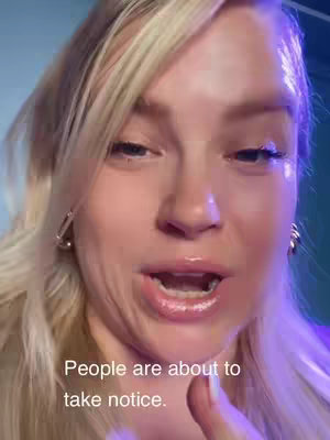 A selfie of a woman with blonde hair, looking towards the camera with an open mouth, as if speaking. The lighting is soft, highlighting her features and giving a clean look.