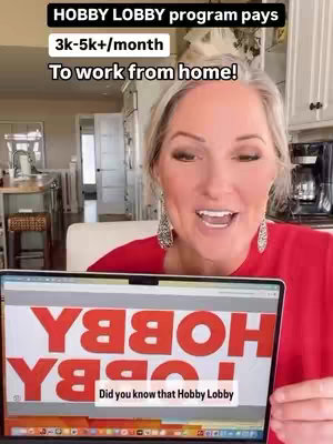 A woman in a red top stands in front of a laptop screen that displays the words 'HOBBY' in large red letters and 'LOBBY'. Above her in the frame is text mentioning a program and pay, including 'To work from home!' The background includes blurred elements of a kitchen area.