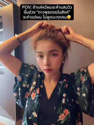 A woman with light skin is holding her hair up with both hands, wearing a dark floral patterned top. Text in the upper left describes the video's premise.