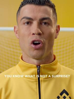 Cristiano Ronaldo is in the center of the frame, with a yellow background and a blurred yellow soccer net behind him. He is wearing a yellow jacket. At the bottom of the frame, text overlays.