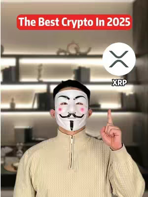 A person wearing a Guy Fawkes mask and a light-colored sweater stands in front of a shelf filled with books and art pieces. Above the person's head is a red banner with the text "The Best Crypto In 2025". To the right is a white circle with the XRP cryptocurrency logo and the text "XRP". The person is pointing their right index finger upwards in a gesture suggesting emphasis or instruction.