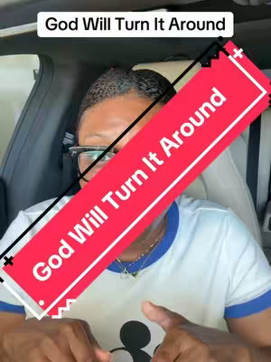 A person in a car interior is the main focus.  They are wearing glasses and what looks to be a white t-shirt with blue trim, and a necklace. A large, diagonal red banner with white text that reads "God Will Turn It Around" overlays the image. A top white banner also contains text, "God Will Turn It Around."