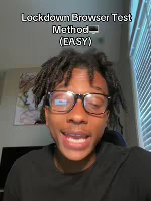 A young man with dark skin and black-framed glasses is in the center of the frame, facing the camera and speaking animatedly. He has dark hair styled into dreadlocks. Above him is overlaid text in white, announcing the video topic. The background is blurred, suggesting an indoor setting, with a glimpse of a window covered by blinds.