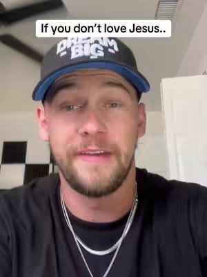 A man in a black shirt and a Dream Big baseball cap is looking directly at the camera and speaking. Text overlay at the top says, "If you don't love Jesus..". The background includes a ceiling fan and a textured wall.