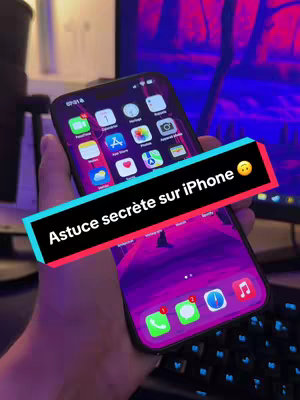 A hand holding a black iPhone displaying its home screen with various app icons. A colorful text overlay in a black and red rectangle reads, "Astuce secrète sur iPhone." The background is a blurred mix of colors and a screen display.